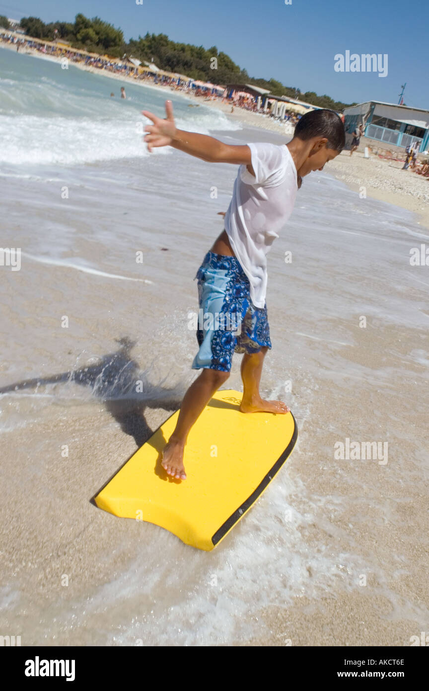 Jeune garçon surf en eau peu profonde Banque D'Images