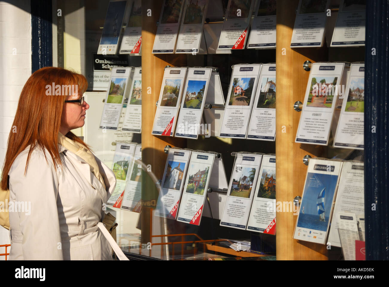 Femme à la recherche de l'agent immobilier à fenêtre, High Street, Cobham, Surrey, Angleterre, Royaume-Uni Banque D'Images