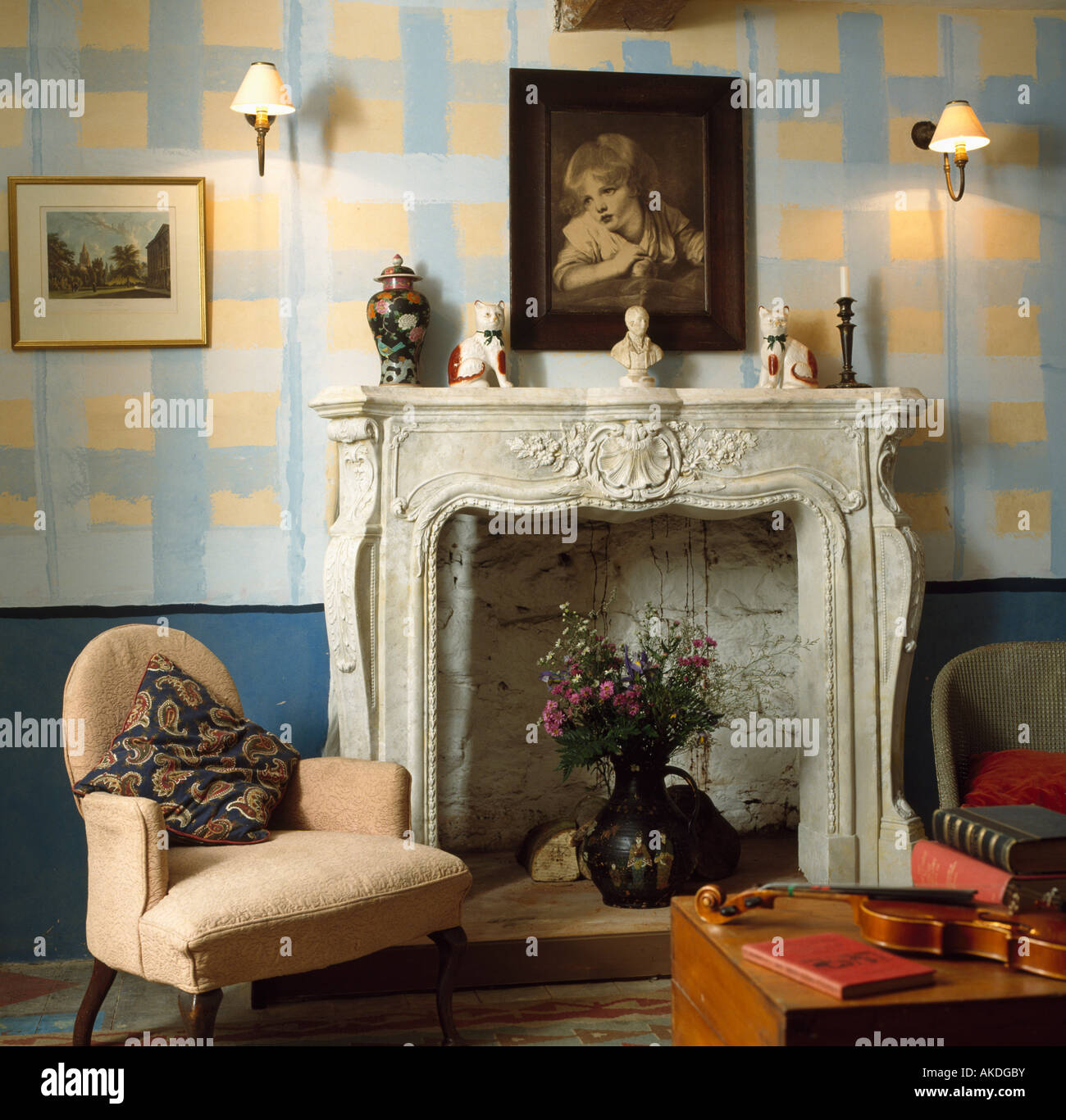 Effet peinture jaune et bleue, vérifier des murs dans un salon avec cheminée en marbre et ornés de petits fauteuil crème Banque D'Images