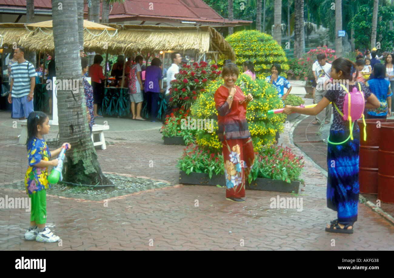 Songkran, Nouvel An Thaï, des profils avec canon à eau en plastique et de l'eau pack arme visant à un enfant dans l'amusement au Parc à thème de Nong Nooch, Pattaya, Thaïlande Banque D'Images