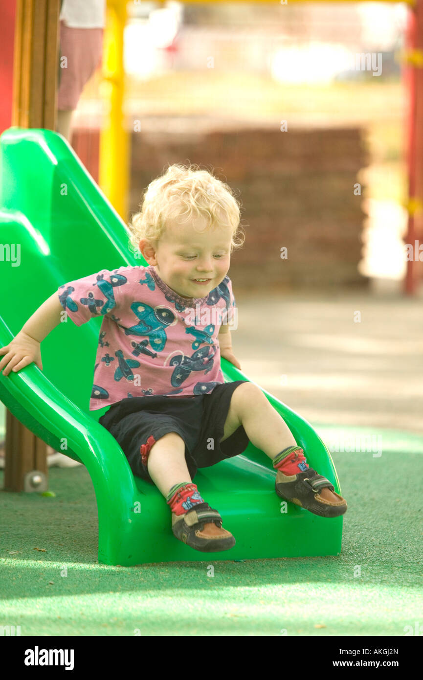 Un bambin jouer sur une diapositive dans une aire de jeux Banque D'Images