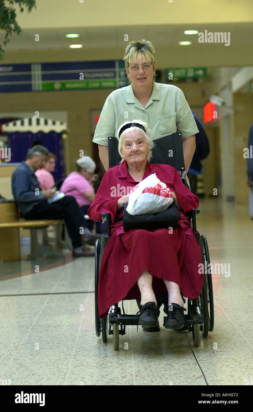 Personnes âgées femme handicapée est pris shopping par sa garde UK Banque D'Images