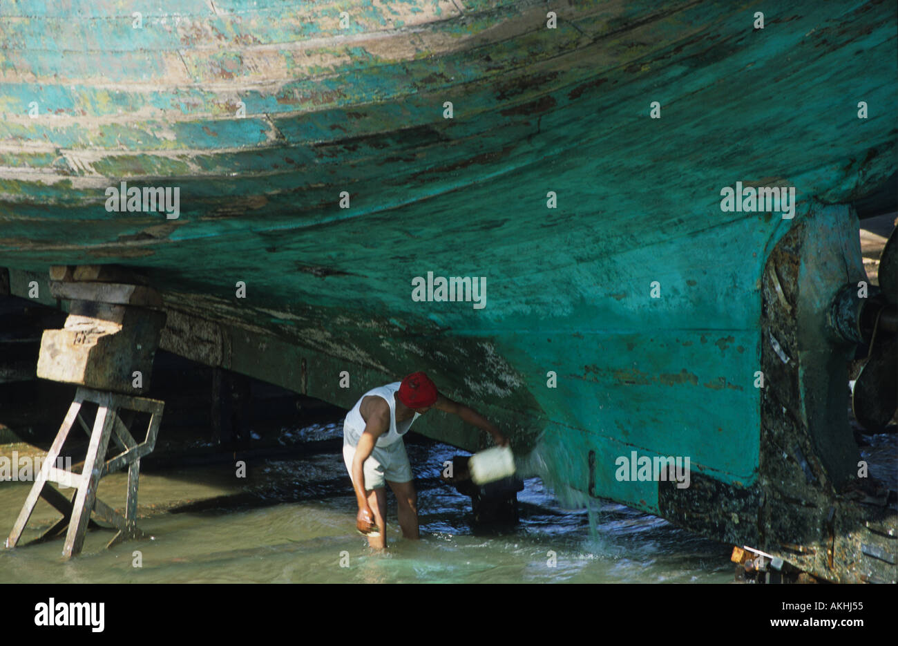 L'homme de la réparation d'un bateau de pêche en bois dans le port, Essaouira, Maroc, Afrique du Nord Banque D'Images