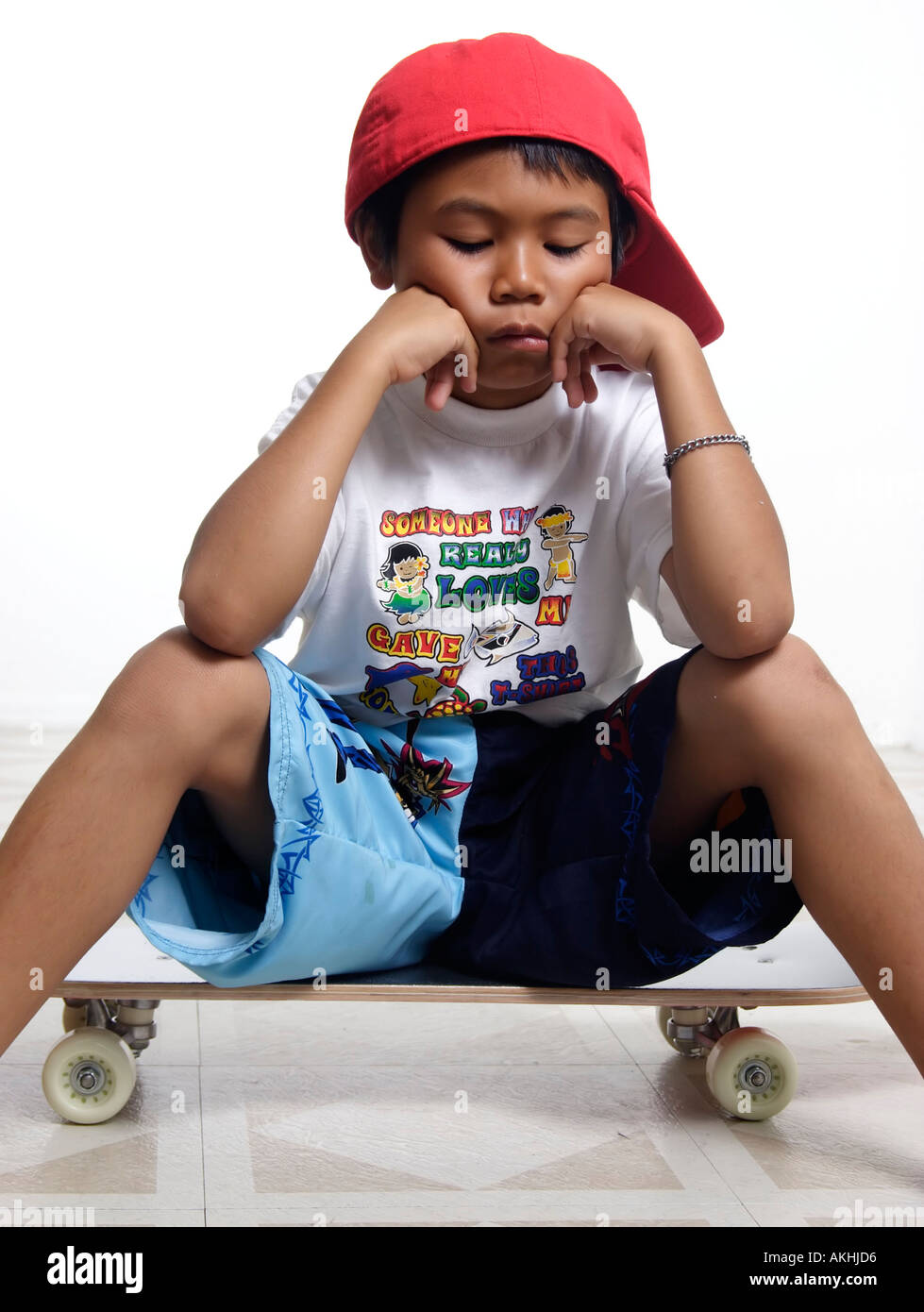 Sad boy sitting on skateboard Photo Stock - Alamy