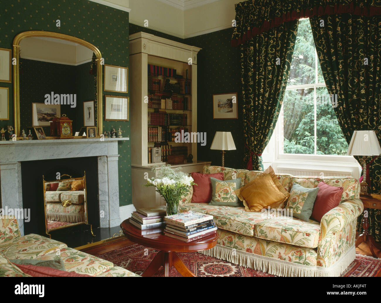 Miroir doré au-dessus de la cheminée de marbre dans années 90 salon papier peint vert rideaux à motifs floral sofas Banque D'Images
