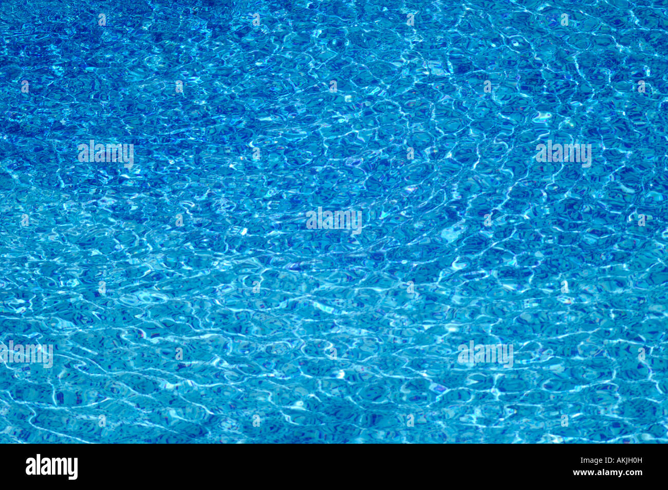 Les ondes à la surface de l'eau créent des motifs aléatoires de la lumière réfractée sur le fond d'une piscine Banque D'Images