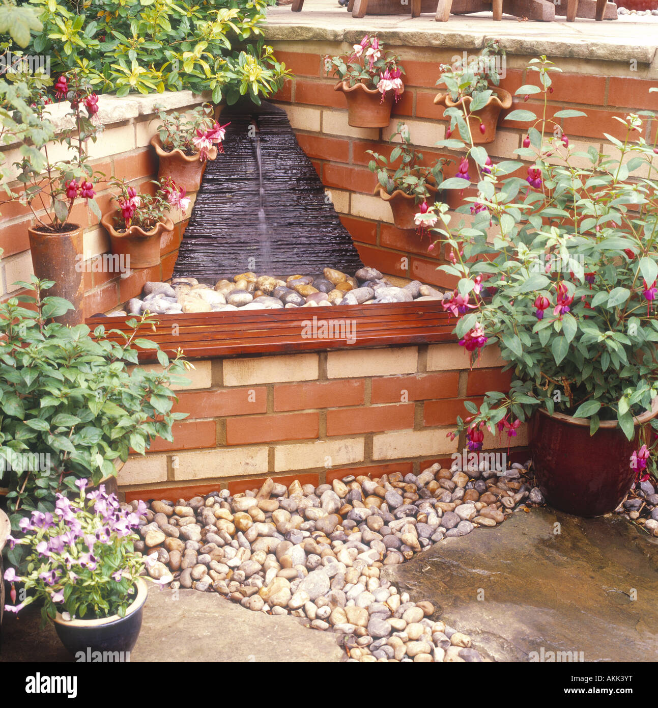 De l'eau banc d'ardoise automne coin jardin plantes fleurs pots brick Banque D'Images