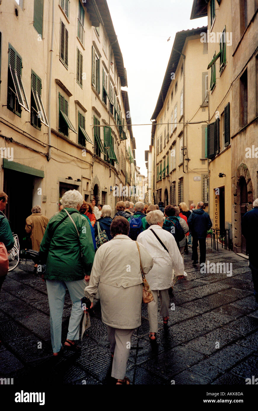 Une ligne de touristes obéissant suivez le guide à travers les rues étroites de la ville de la Renaissance de Lucques en Toscane Italie Banque D'Images