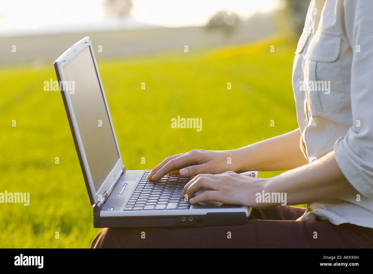 Femme de la saisie sur un ordinateur portable à l'extérieur dans un pré se concentrer uniquement sur la main droite Banque D'Images