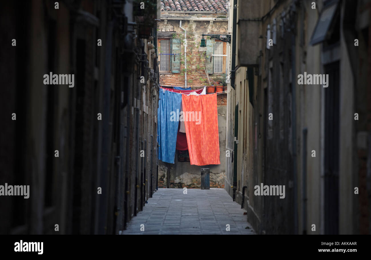 Une fiche rouge et une feuille bleue accrochée à un lave-ligne à la fin d'une rue étroite à Venise, Italie. Banque D'Images