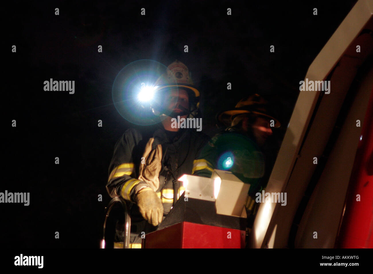 Deux pompiers aux commandes d'un camion dans la nuit avec leurs torches électriques sur Banque D'Images