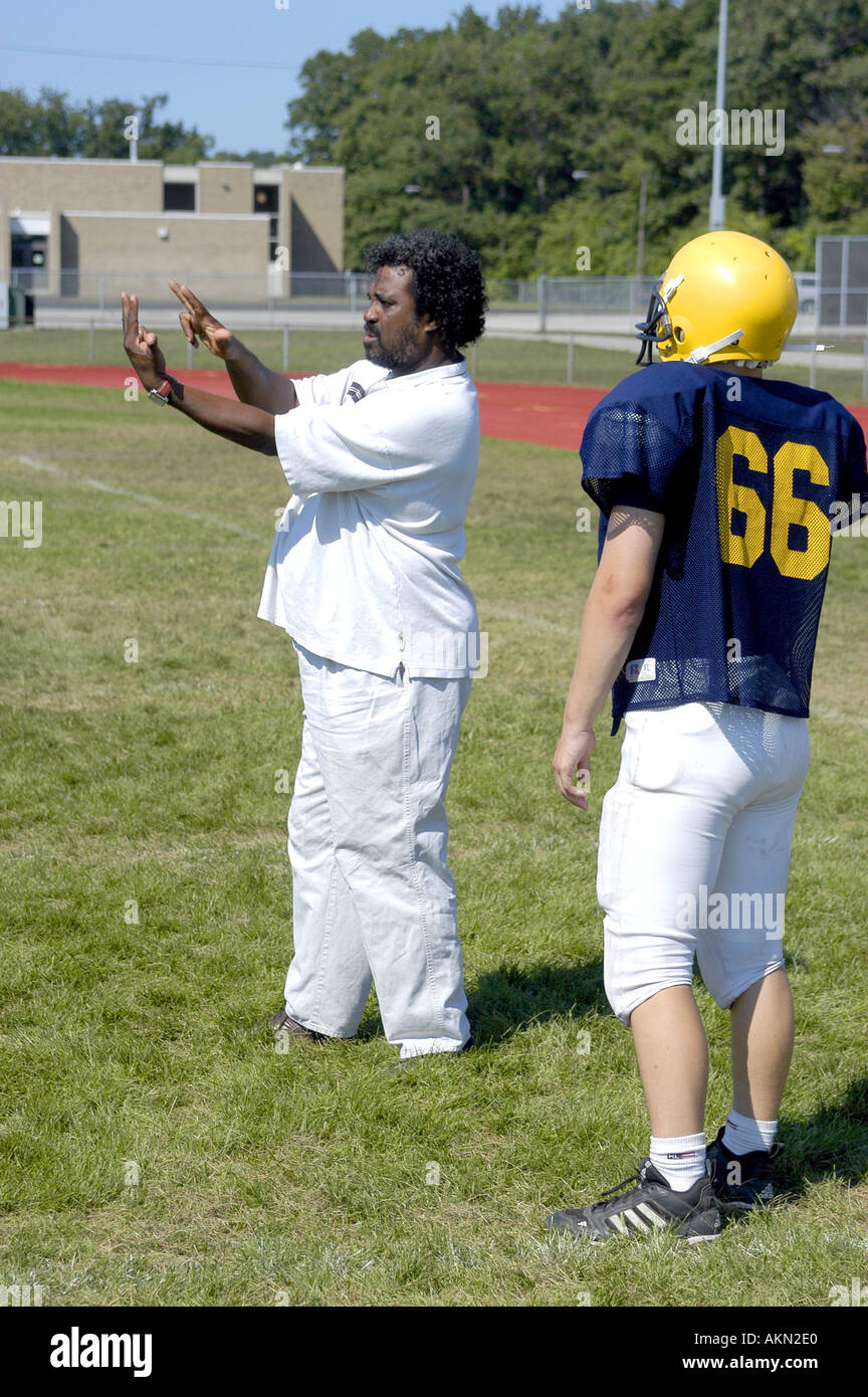L'action de l'école de football de haut Port Huron au Michigan football player lit JV Sourds la langue des signes donnés par l'aide au cours de la pratique noir Banque D'Images
