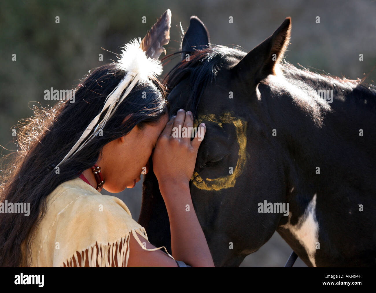 Un Native American Indian boy wearing a feather partager un moment spécial avec son cheval Banque D'Images