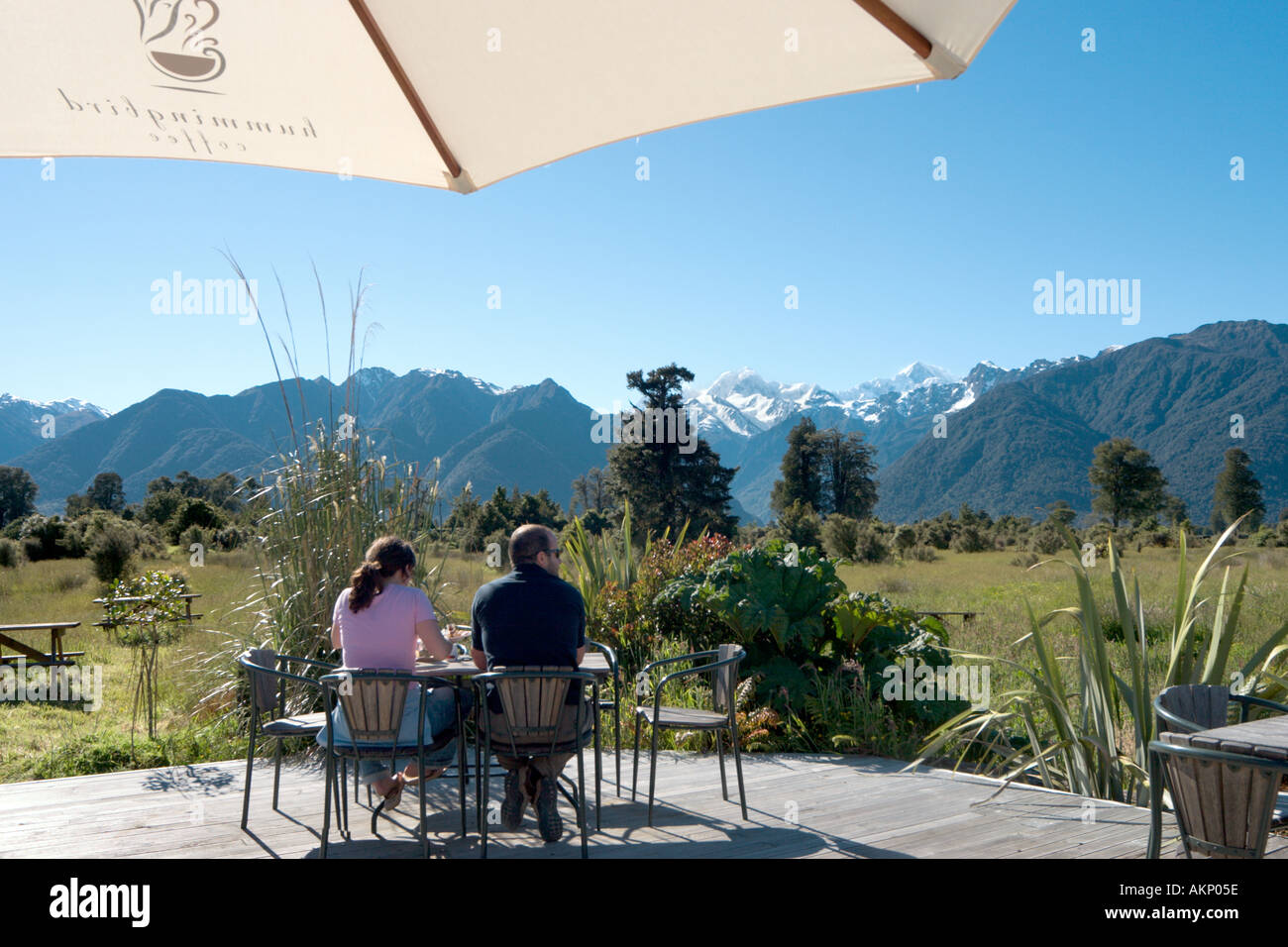 Couple sur une terrasse de café avec vue sur le Mont Cook et le Mont Tasman, près du lac Matheson, Fox Glacier, île du Sud, Nouvelle-Zélande Banque D'Images