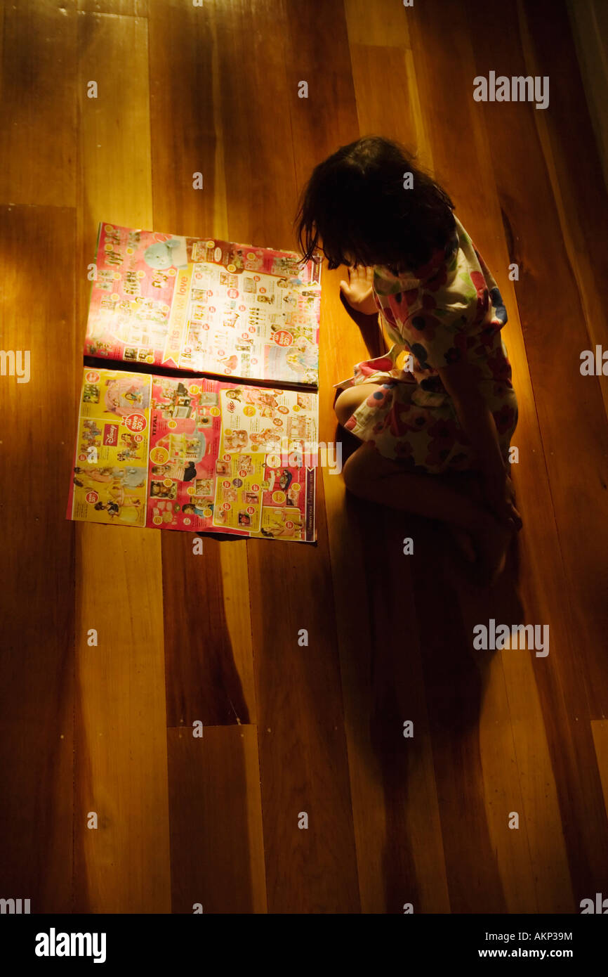 Jeune fille âgée de 4 ans lit toy brochure junk mail Banque D'Images