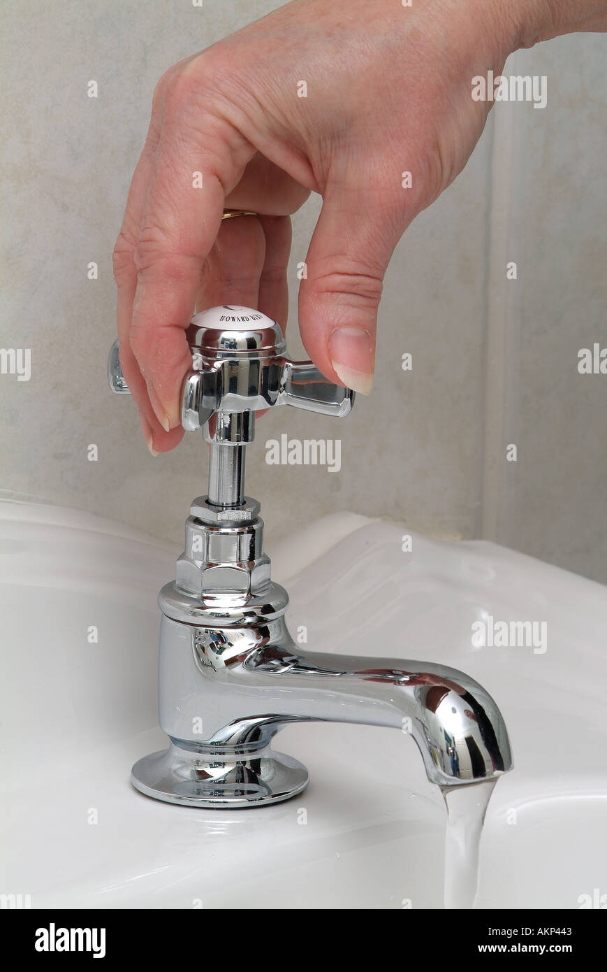 La main de femme tournant un robinet d'eau chrome Banque D'Images