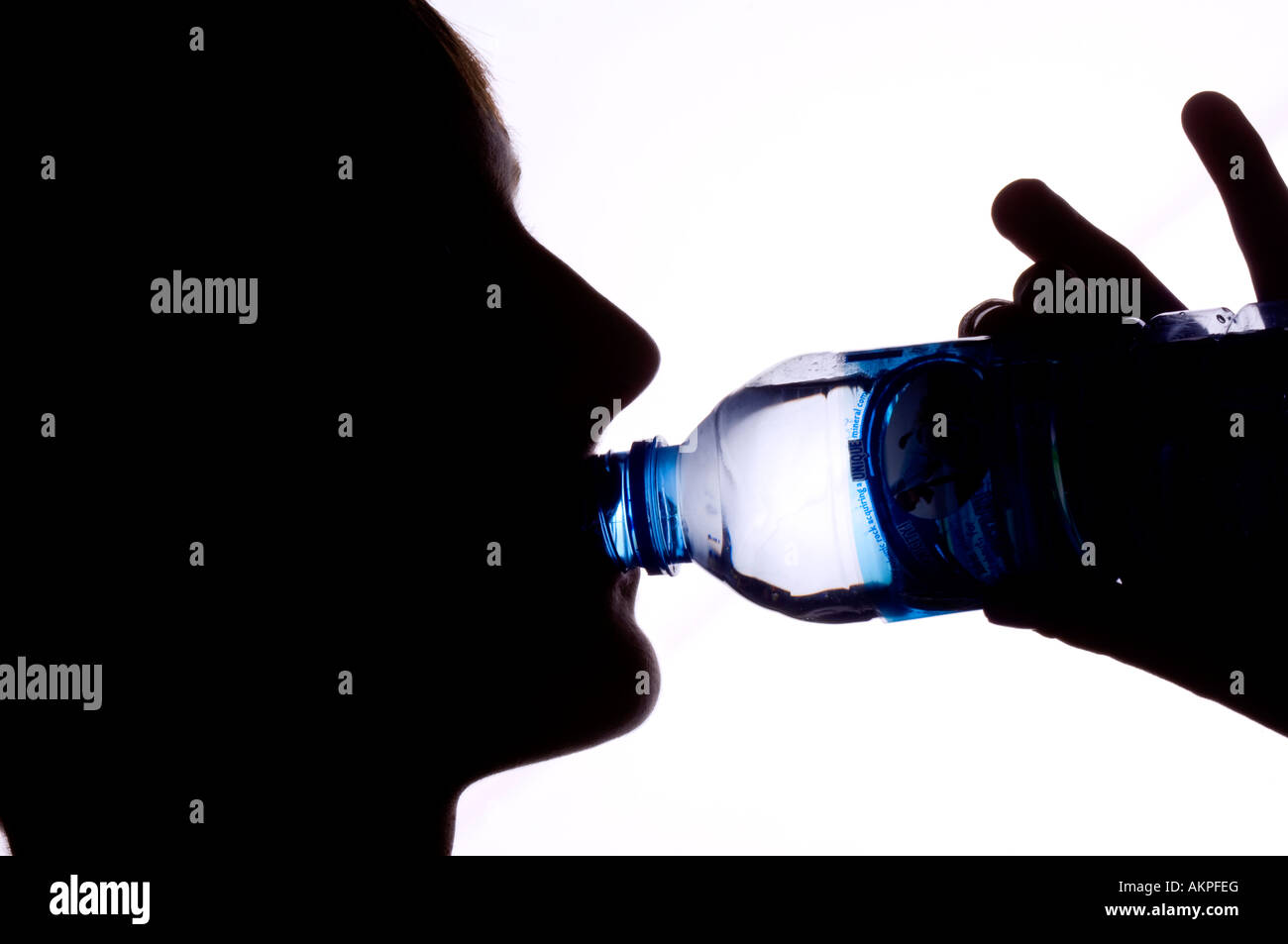 Silhouette d'un adolescent l'eau potable à partir d'une bouteille. Photo par Jim Holden. Banque D'Images