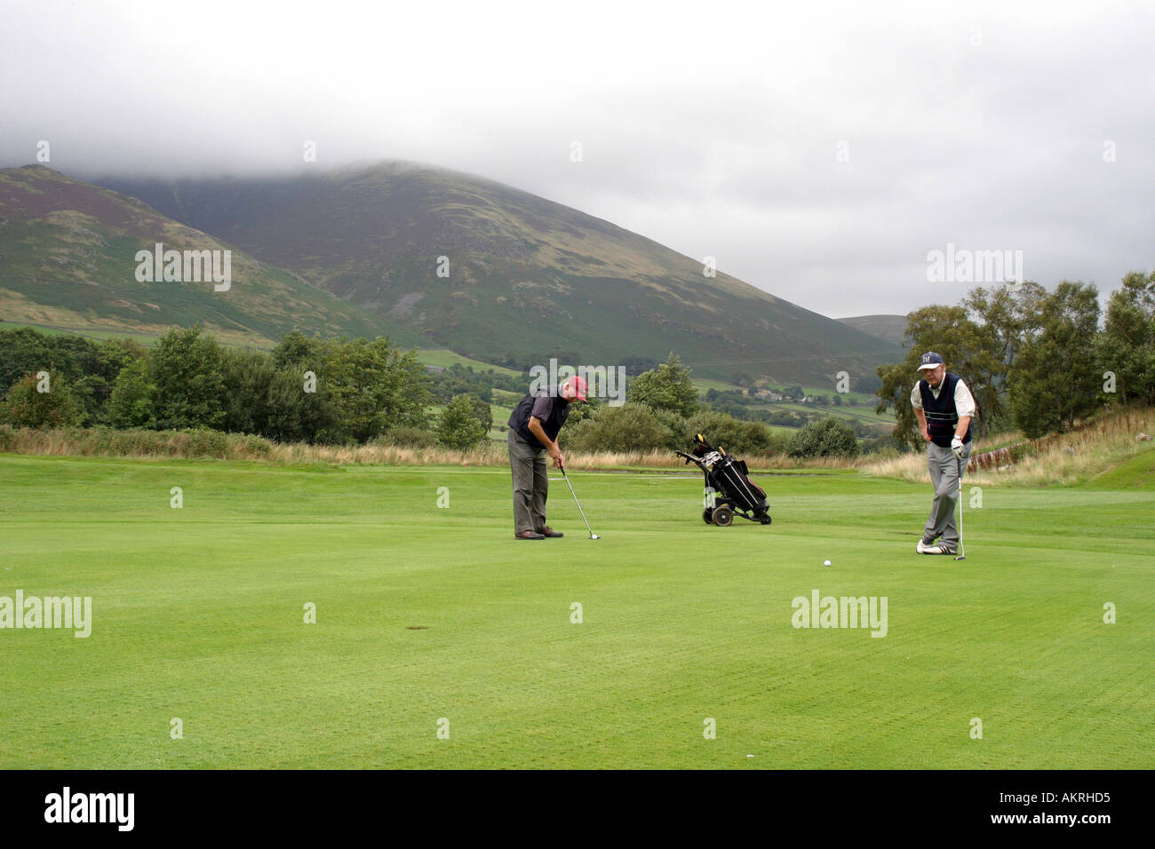 Deux golfeurs sur le parcours ouvert avec les montagnes en arrière-plan Banque D'Images