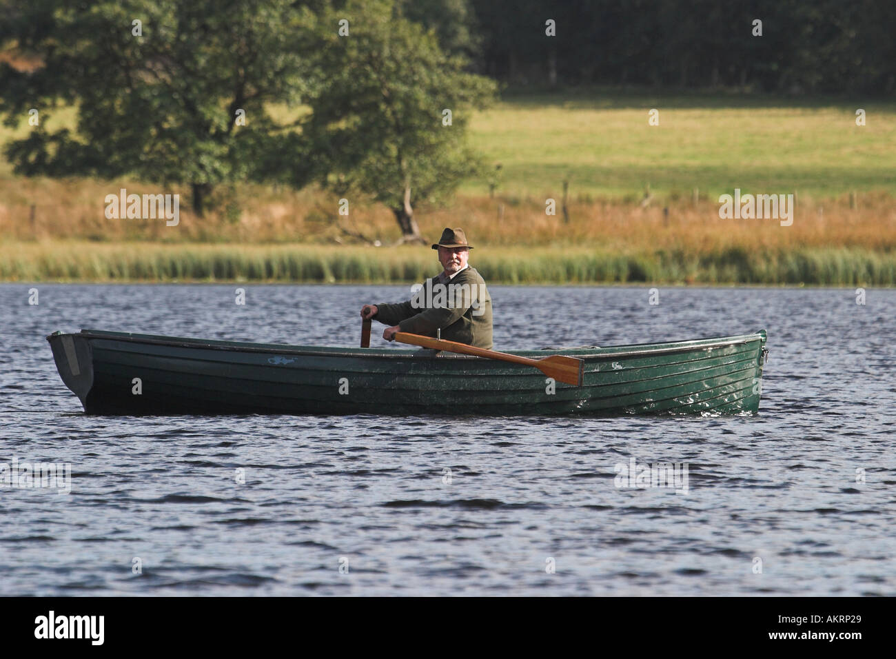 L'homme pêche de mouche sur un tarn dans le lake district Banque D'Images