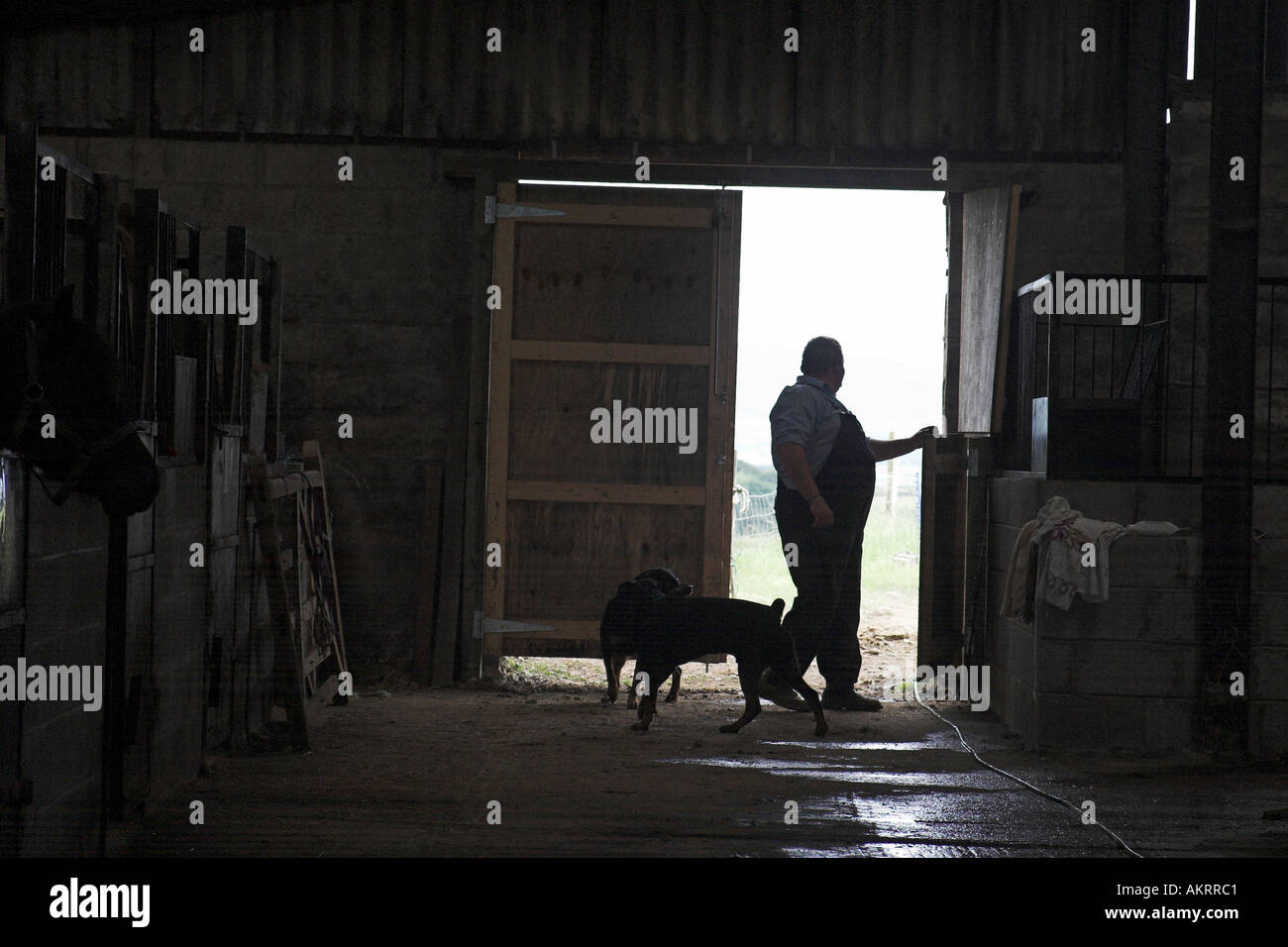 Silhouette d'un agriculteur ouverture portes stables Banque D'Images