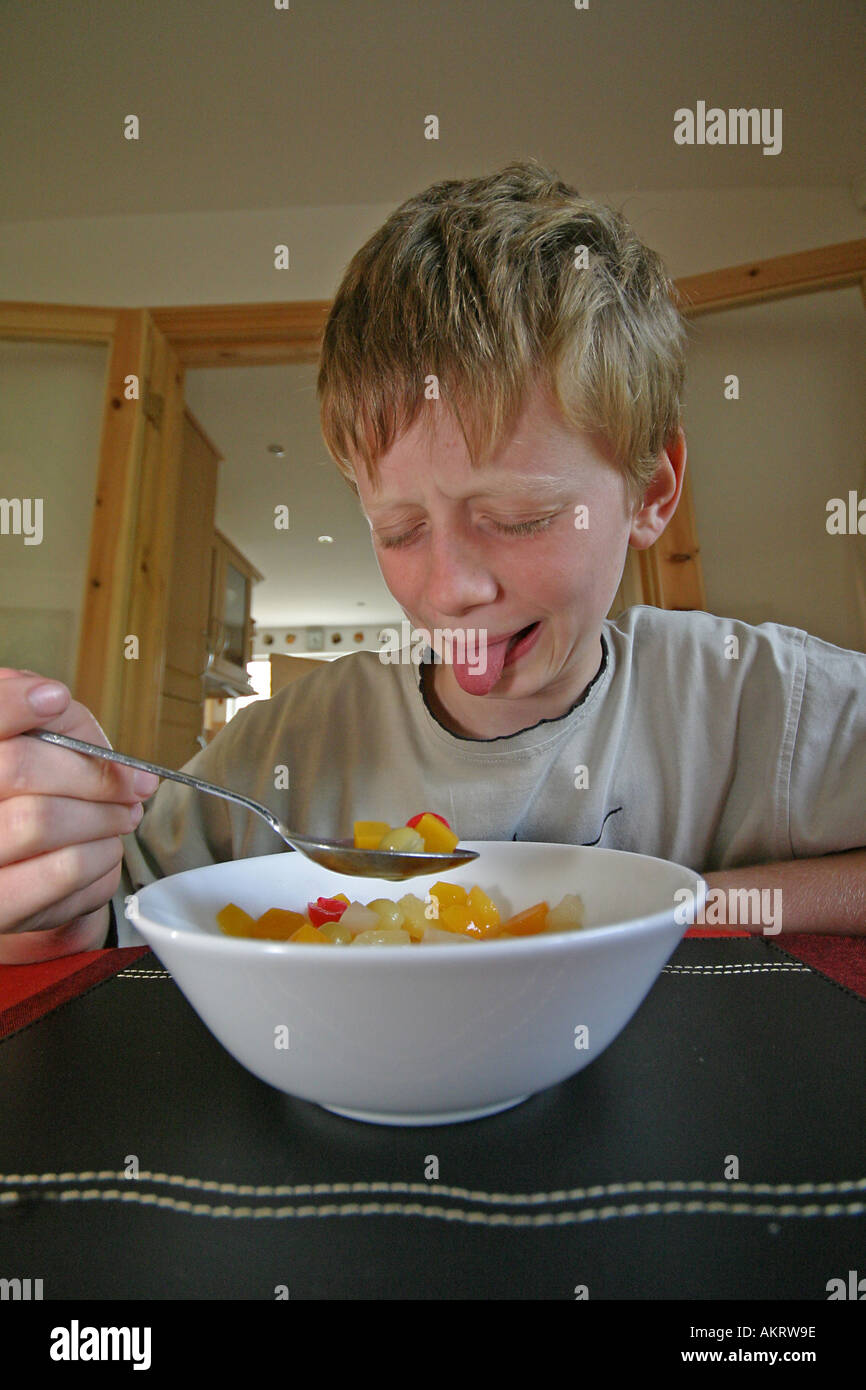Boy eating fruit d'un bol à la maison qu'il ne comme Banque D'Images