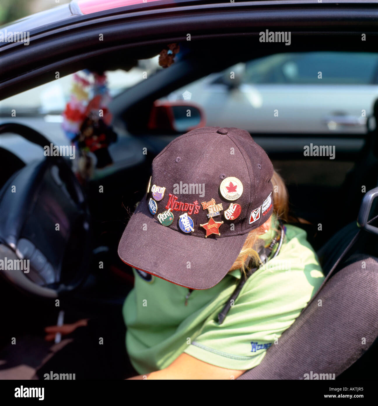 Wendys et logo sur les badges portés par une casquette de Wendys employé en faisant une pause dans sa voiture, Canada Banque D'Images