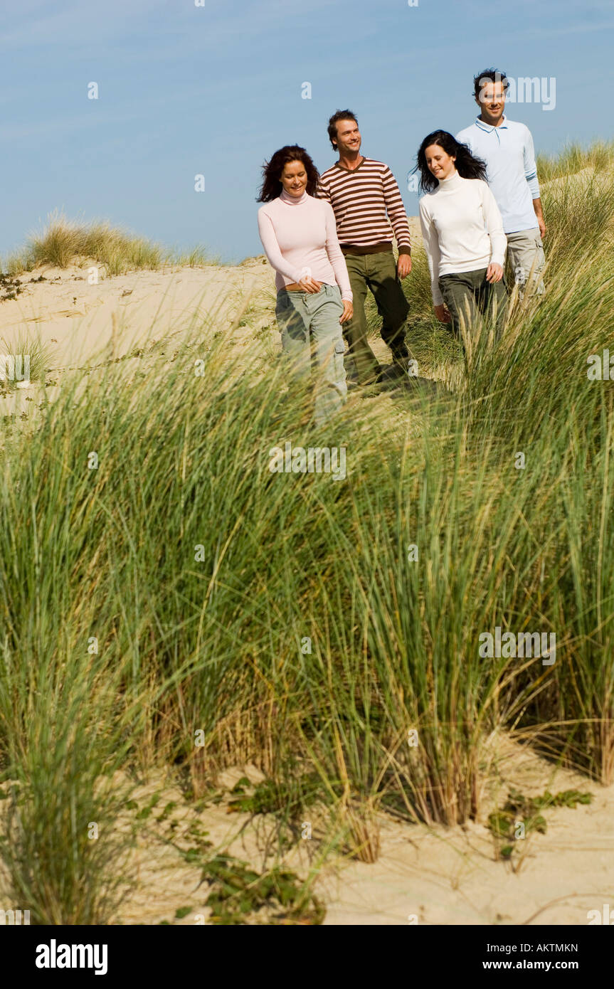 Quatre amis marchant sur la plage Banque D'Images