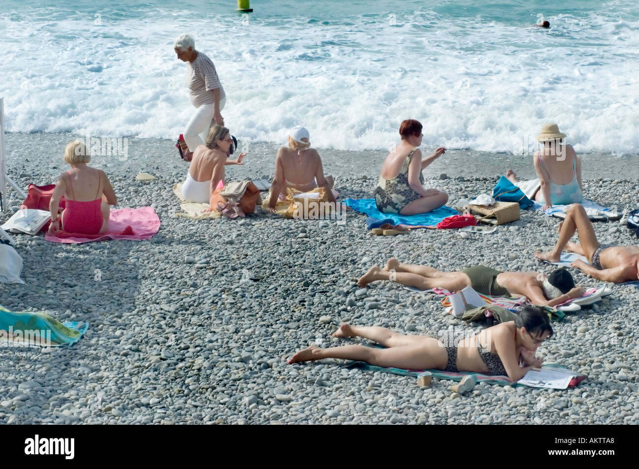Nice, France scène de plage Mid Adult femmes bains de soleil près de l'océan dans les combinaisons de bain en vacances détente, vue arrière du groupe d'aînés Banque D'Images