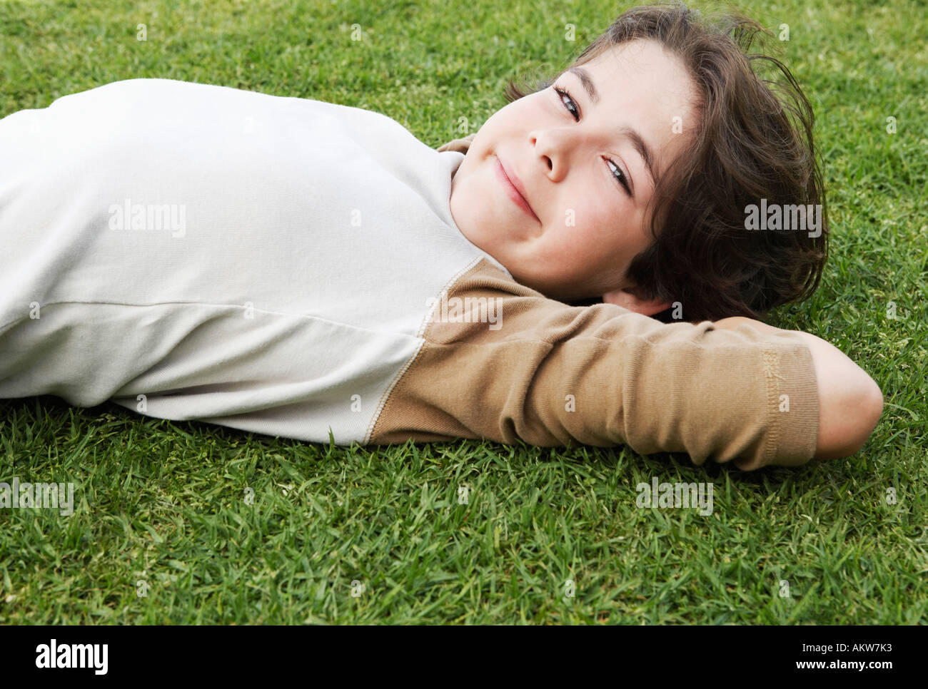 Pré-ado garçon couché sur le dos dans l'herbe, les mains derrière la tête,  vue du sol Photo Stock - Alamy