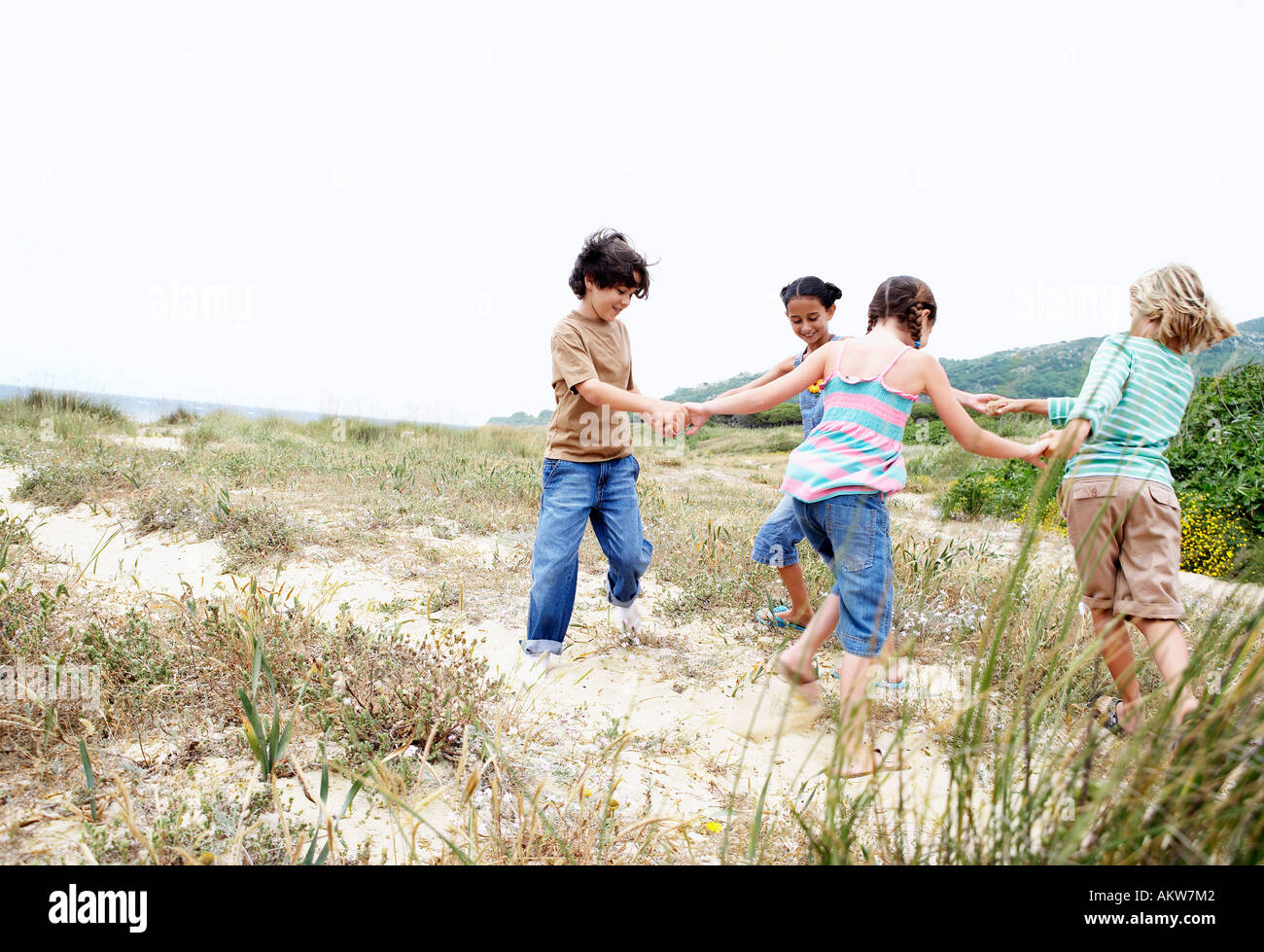 Enfants jouant autour de l'anneau rose sur la plage d'herbe Banque D'Images