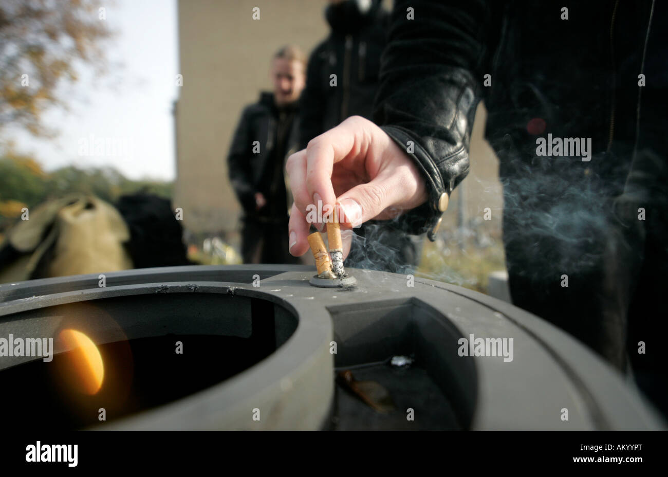 Un élève fumeur met sa cigarette dans un bac à cendres Banque D'Images