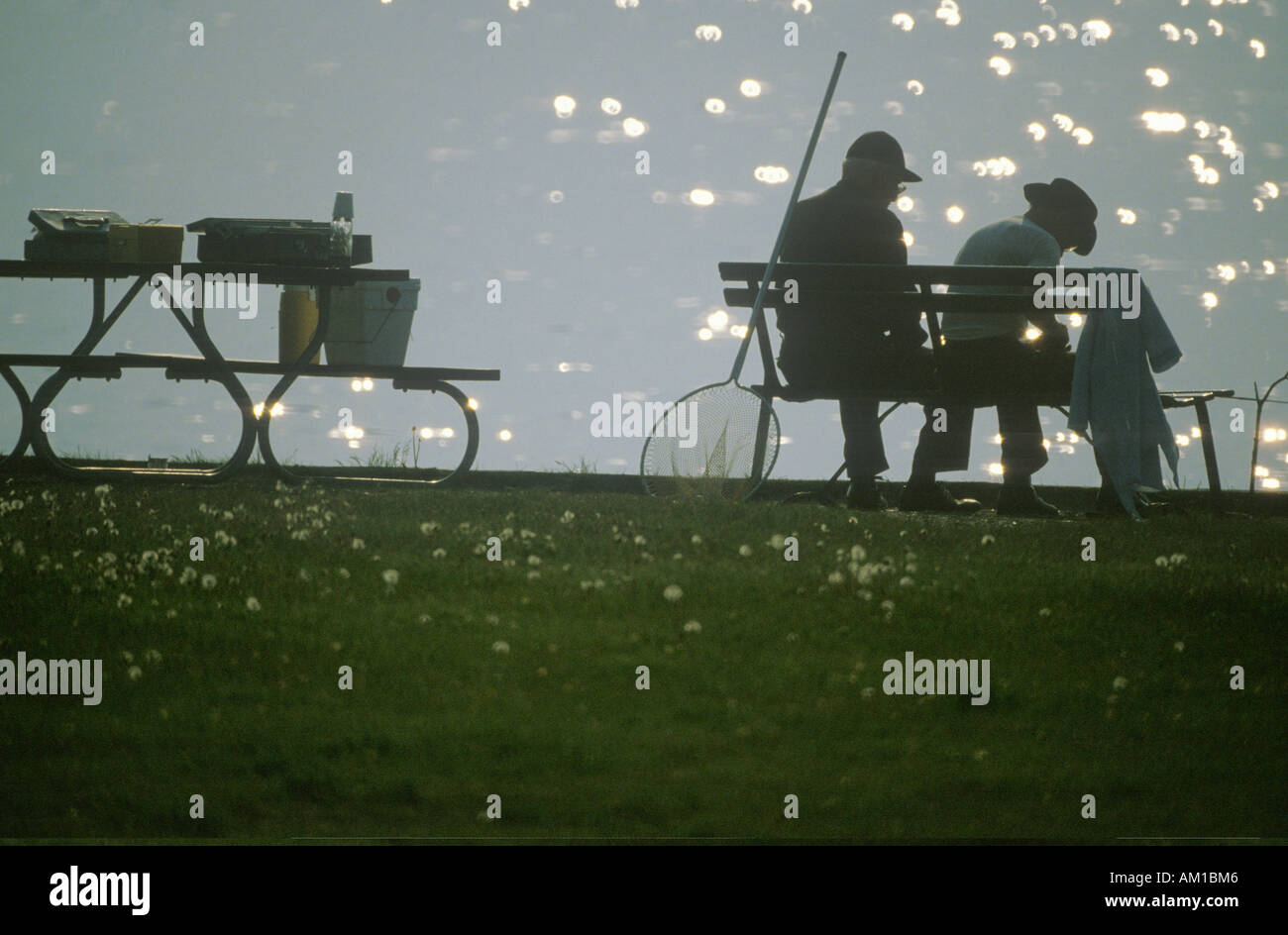 Silhouette de 2 pêcheurs sur banc avec poteaux MI Banque D'Images