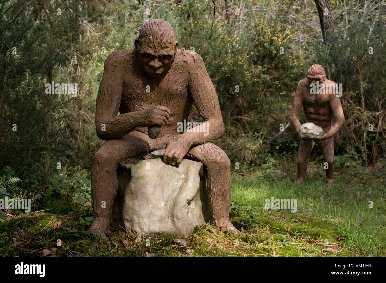 Taille de la vie de l'Homo erectus assis à l'aide de modèles d'outils de pierre Dinosaur Park France Banque D'Images