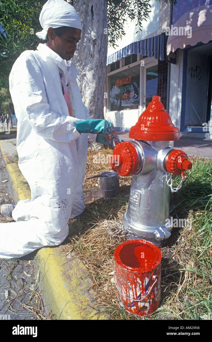 Un homme en peinture d'un poteau incendie à South Beach Miami Floride Banque D'Images