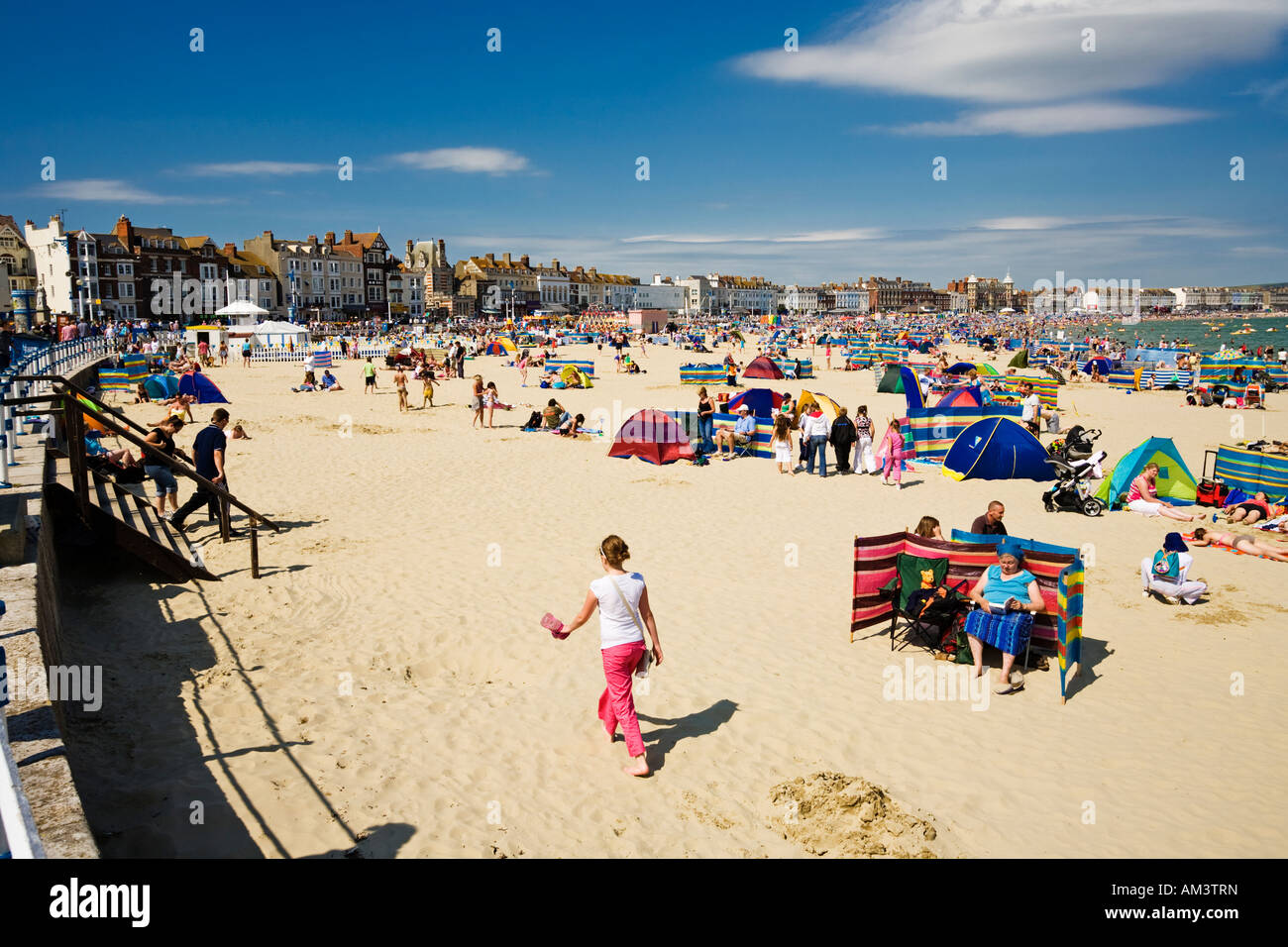 Les gens au bord de la mer bronzer sur la plage de Weymouth en été, côte du Dorset, Angleterre, Royaume-Uni Banque D'Images
