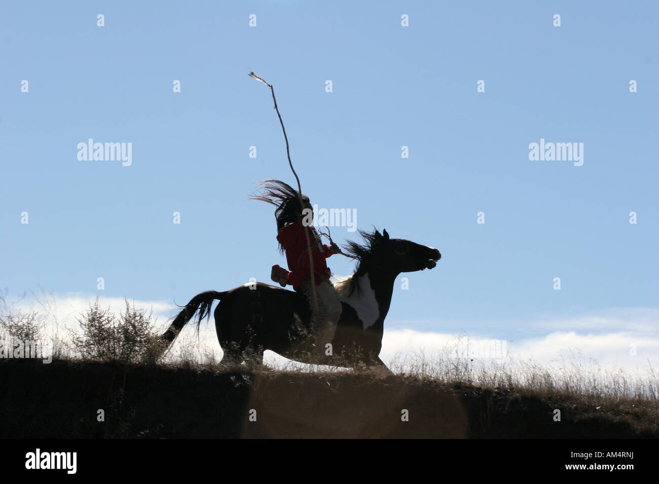 Un Native American Indian man qui se profile l'équitation à ememies à travers la prairie du Dakota du Sud Banque D'Images