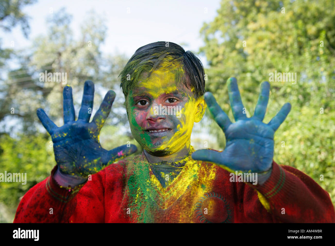 Un jeune garçon, montre son visage et les mains de couleur au cours du festival Holi en Inde. Banque D'Images