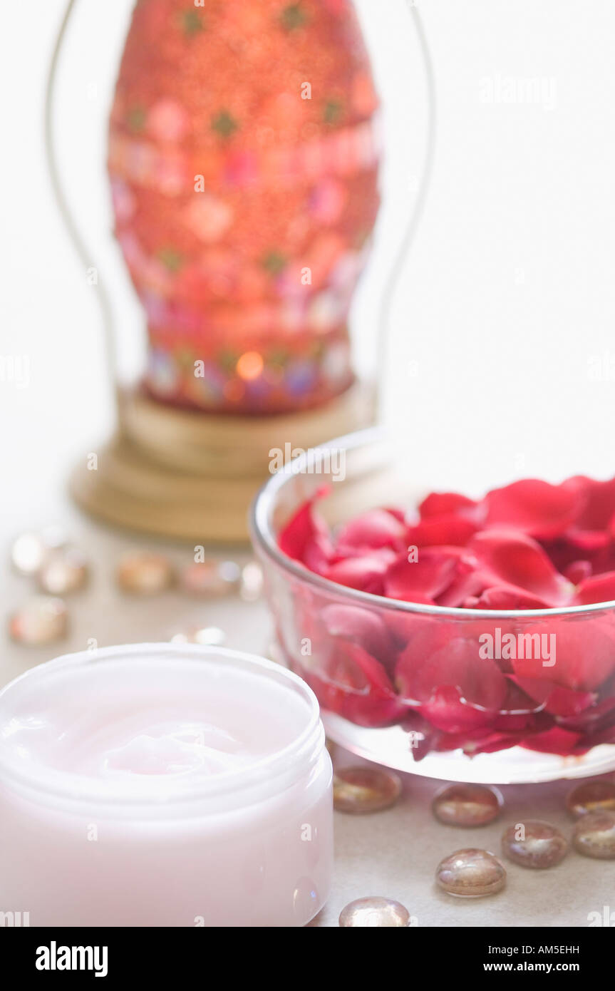 Close-up de pétales de rose dans un bol avec la crème hydratante et une lanterne Banque D'Images
