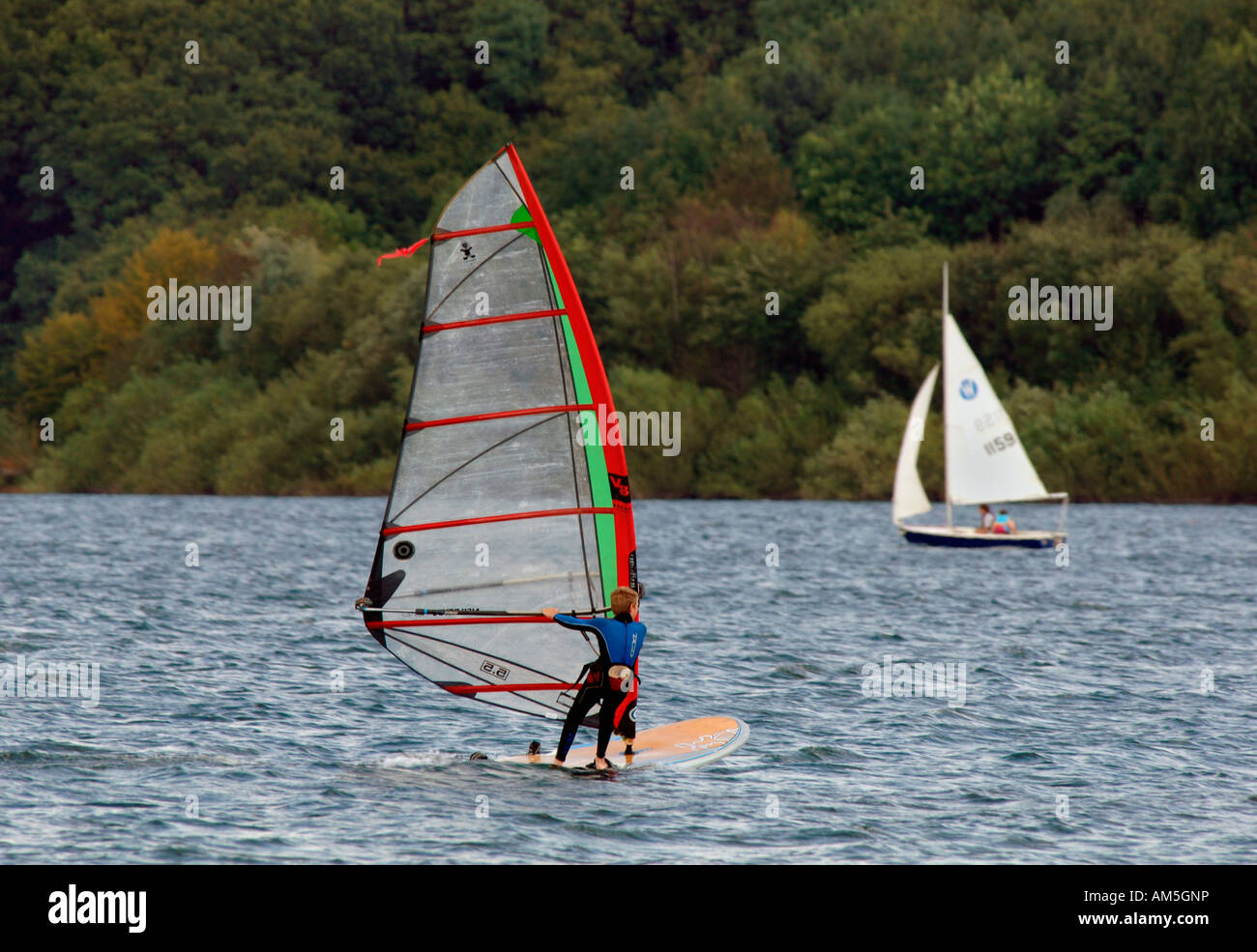 Planche à voile et voile sur l'eau du réservoir d'eau douce Carsington dans le Derbyshire en Angleterre Banque D'Images