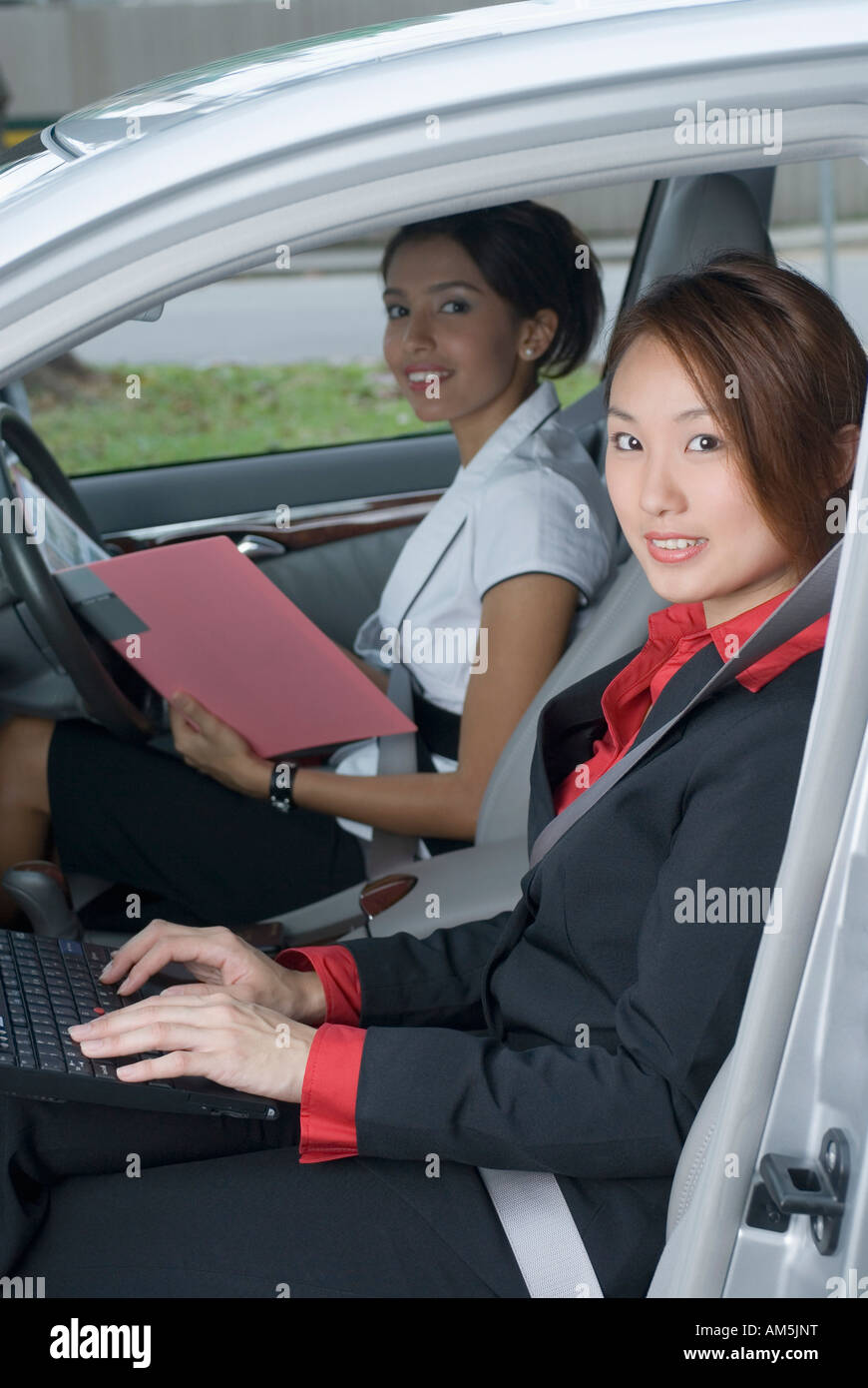 Portrait of two businesswomen assise dans une voiture et de travail Banque D'Images