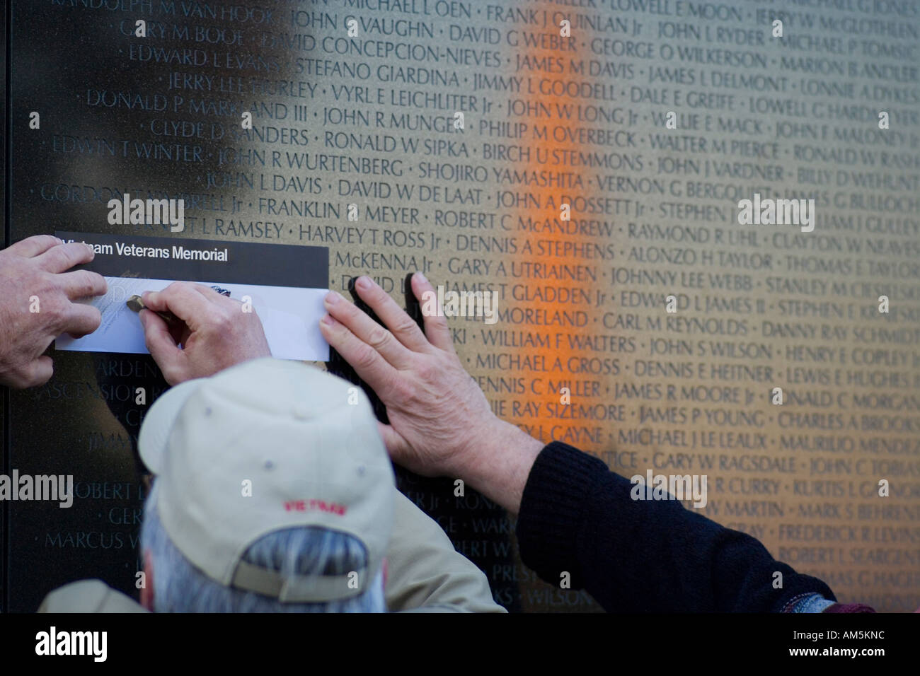 Les hommes âgés en frottant un crayon nom d'un membre de la famille tombée au mur ; la Vietnam Veterans Memorial à Washington D.C. Banque D'Images