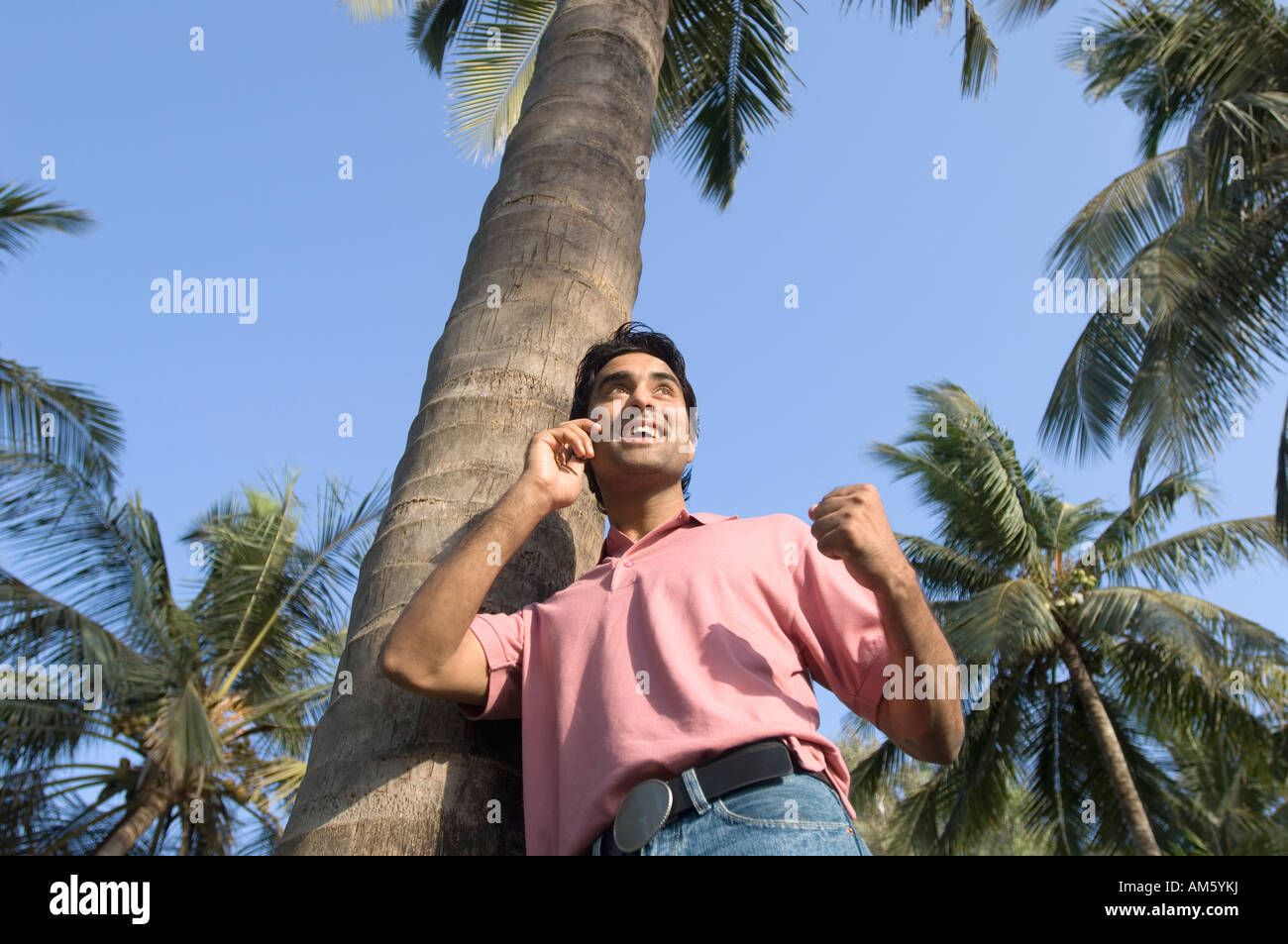 Portrait d'un jeune homme appuyé contre un arbre et de parler sur un téléphone mobile Banque D'Images