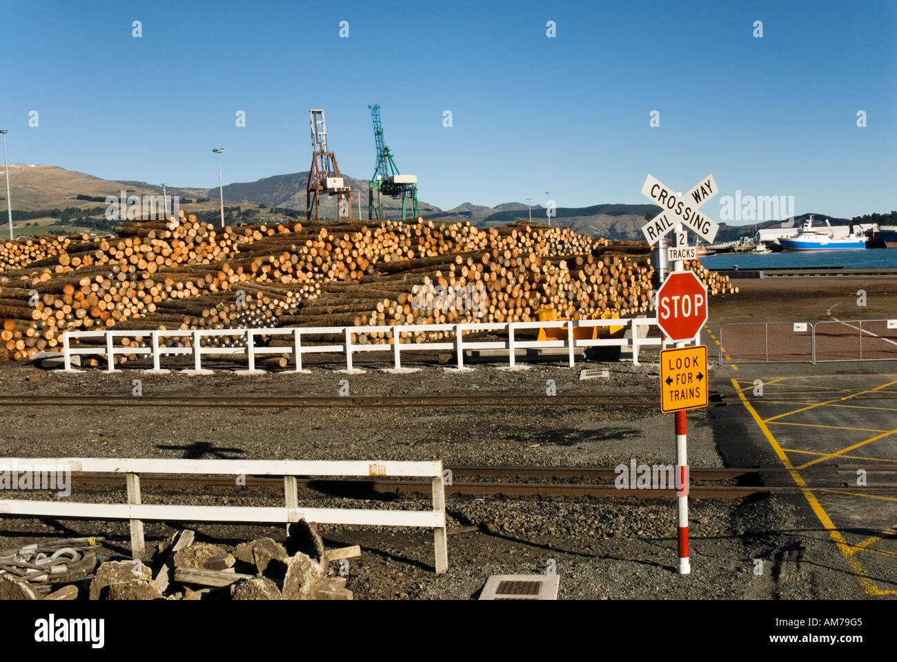 Vue sur la voie ferrée à des piles de bois en attente de chargement au port de Lyttelton en Nouvelle-Zélande Banque D'Images
