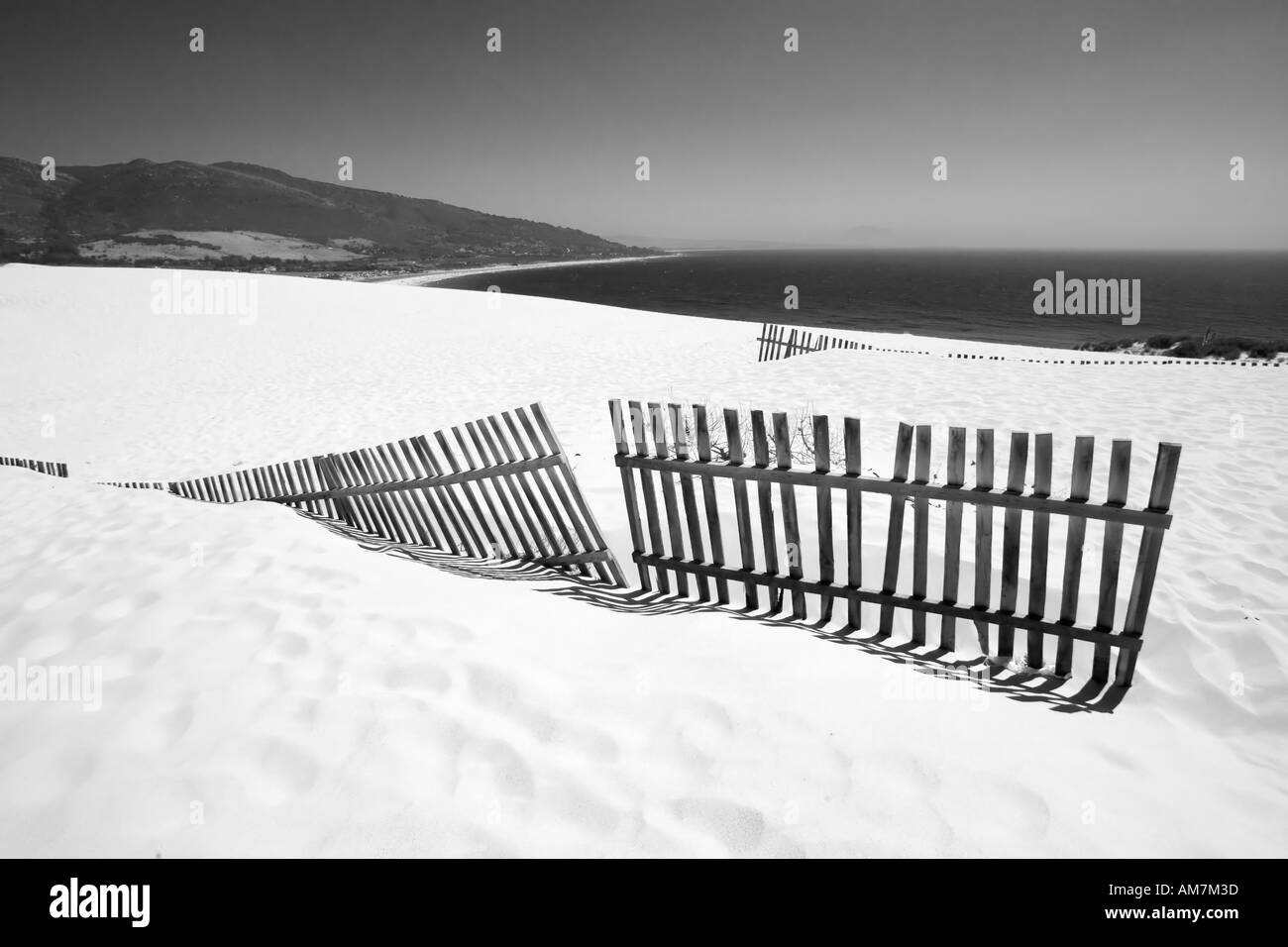 Vieille clôture dépassant de dunes de sable déserte Banque D'Images