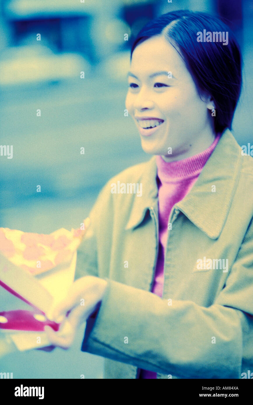 Young woman holding pizza, smiling Banque D'Images