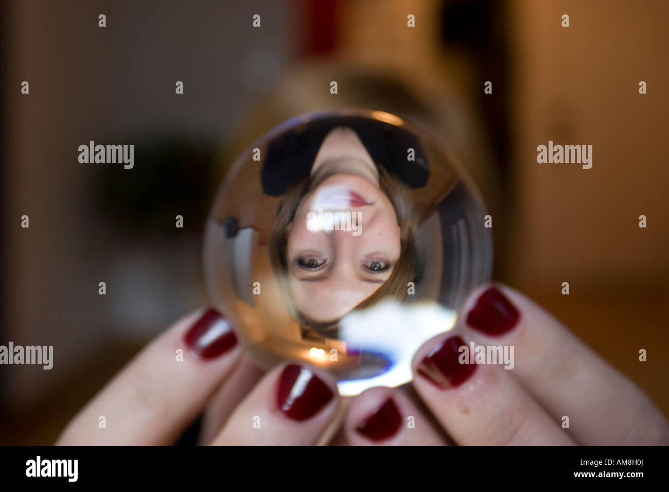 Femme tenant une sphère de verre avec son image réfractée à l'intérieur tout en se tenant dans vide appartement new-yorkais Banque D'Images