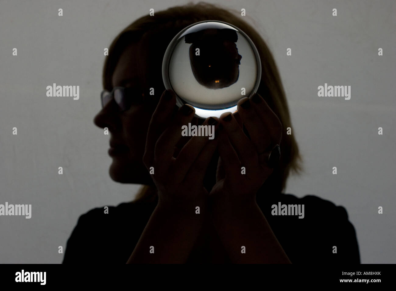 Femme tenant une sphère de verre avec son image réfractée à l'intérieur tout en se tenant dans vide appartement new-yorkais Banque D'Images