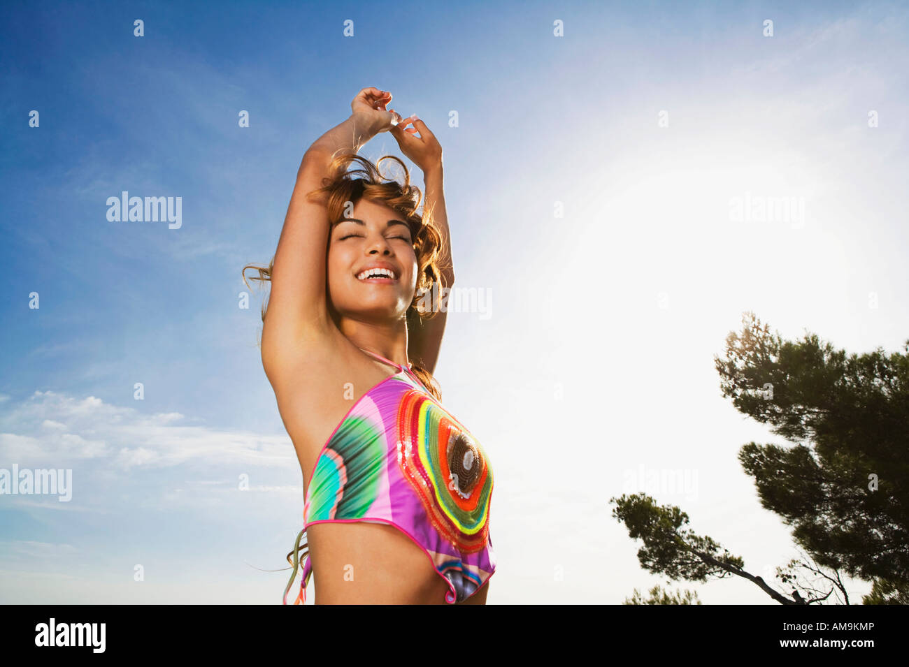 Woman standing outdoors with arms raised souriant. Banque D'Images