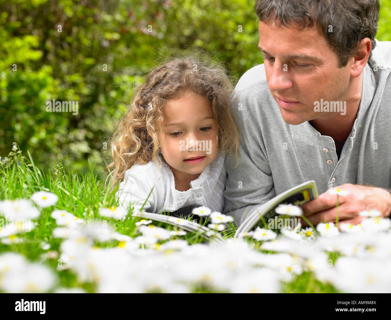 L'homme et de la jeune fille allongée dans l'herbe la lecture. Banque D'Images