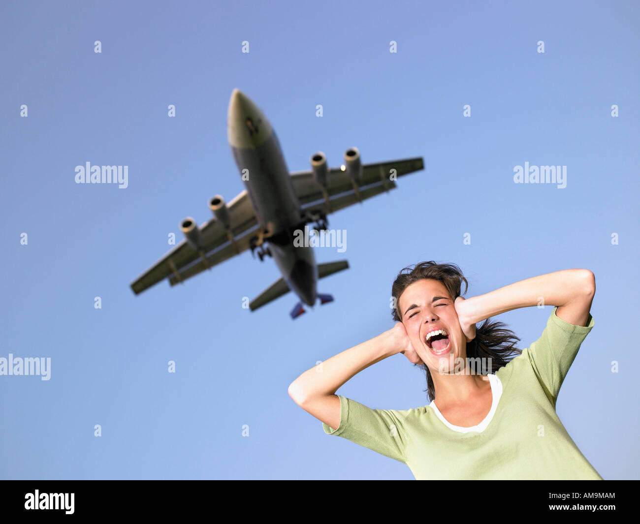 Femme couvrant les oreilles et de crier avec avion volant au-dessus. Banque D'Images